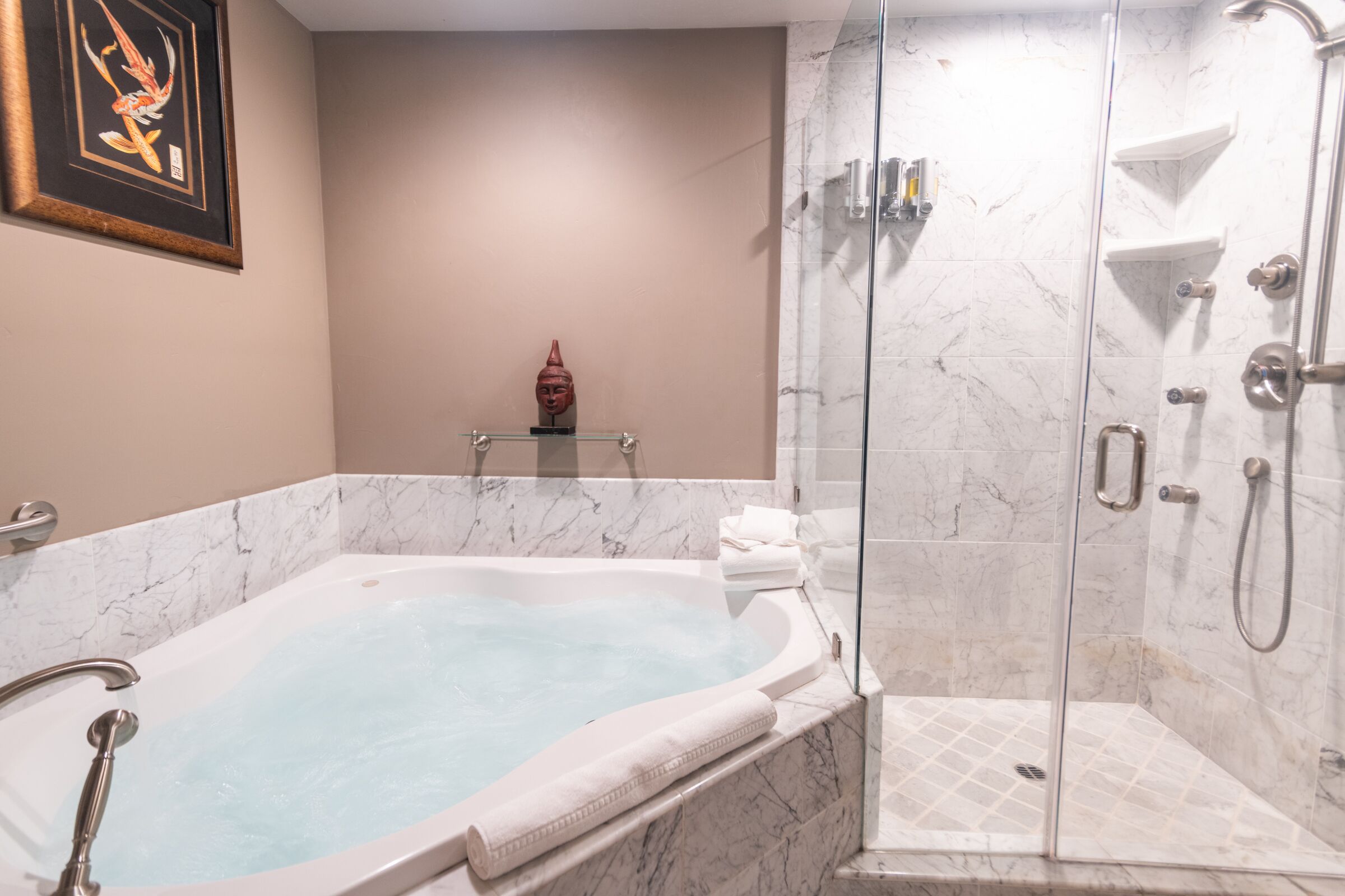 A modern bathroom with a marble bathtub, a glass-enclosed shower, and a minimalist design.