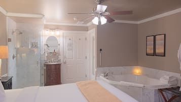 A hotel room with a bed, a bathroom with a bathtub, a shower, and a ceiling fan.