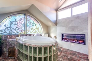 A bathroom with a freestanding bathtub, a glass shower enclosure, and a fireplace.