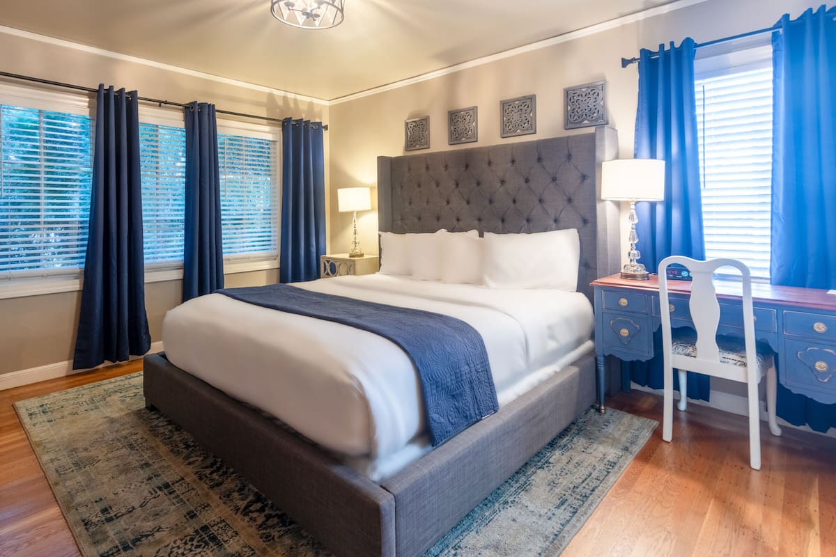 A bedroom with a large bed, a desk, and a chair.