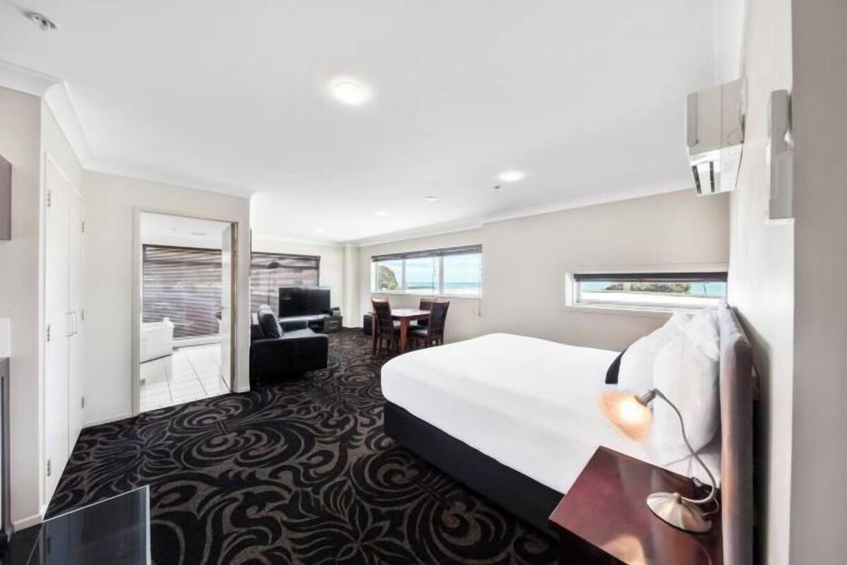 Habitación de hotel con una cama grande, un escritorio y vistas al exterior.