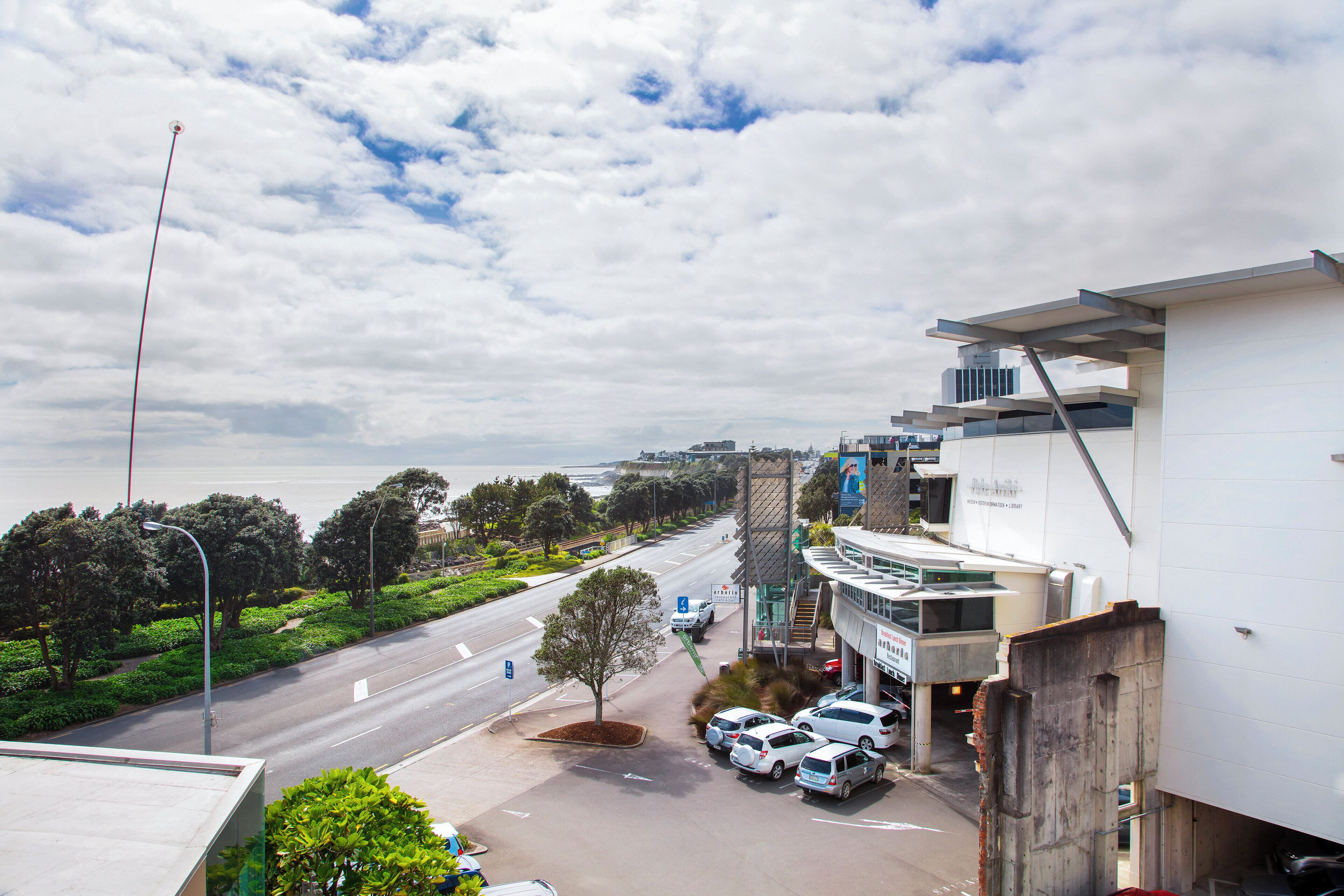 Um edifício moderno com estacionamento e uma estrada que leva ao mar.