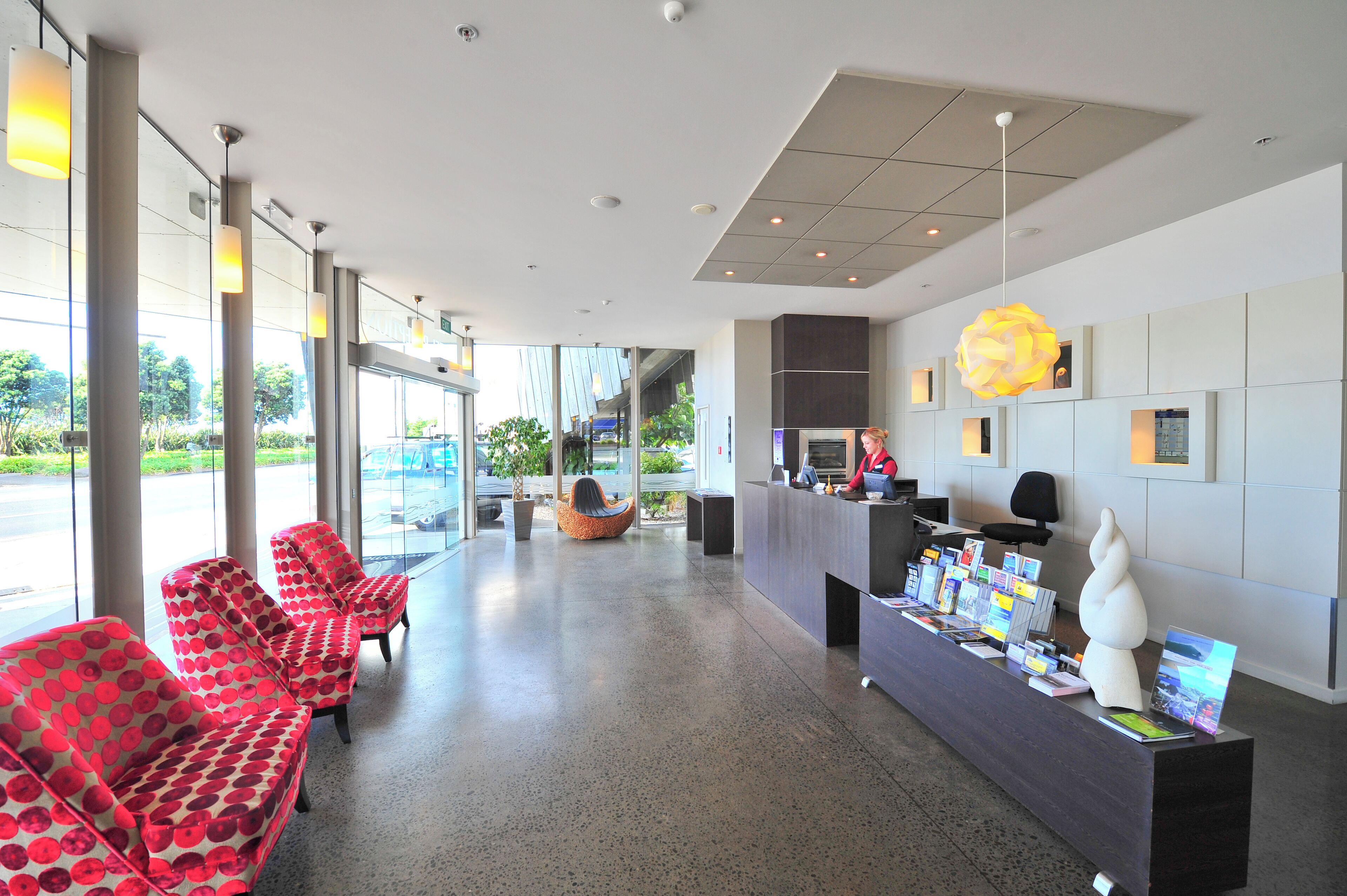 A modern reception area with a reception desk, seating area with patterned chairs, and a large window providing a view of the outdoors.