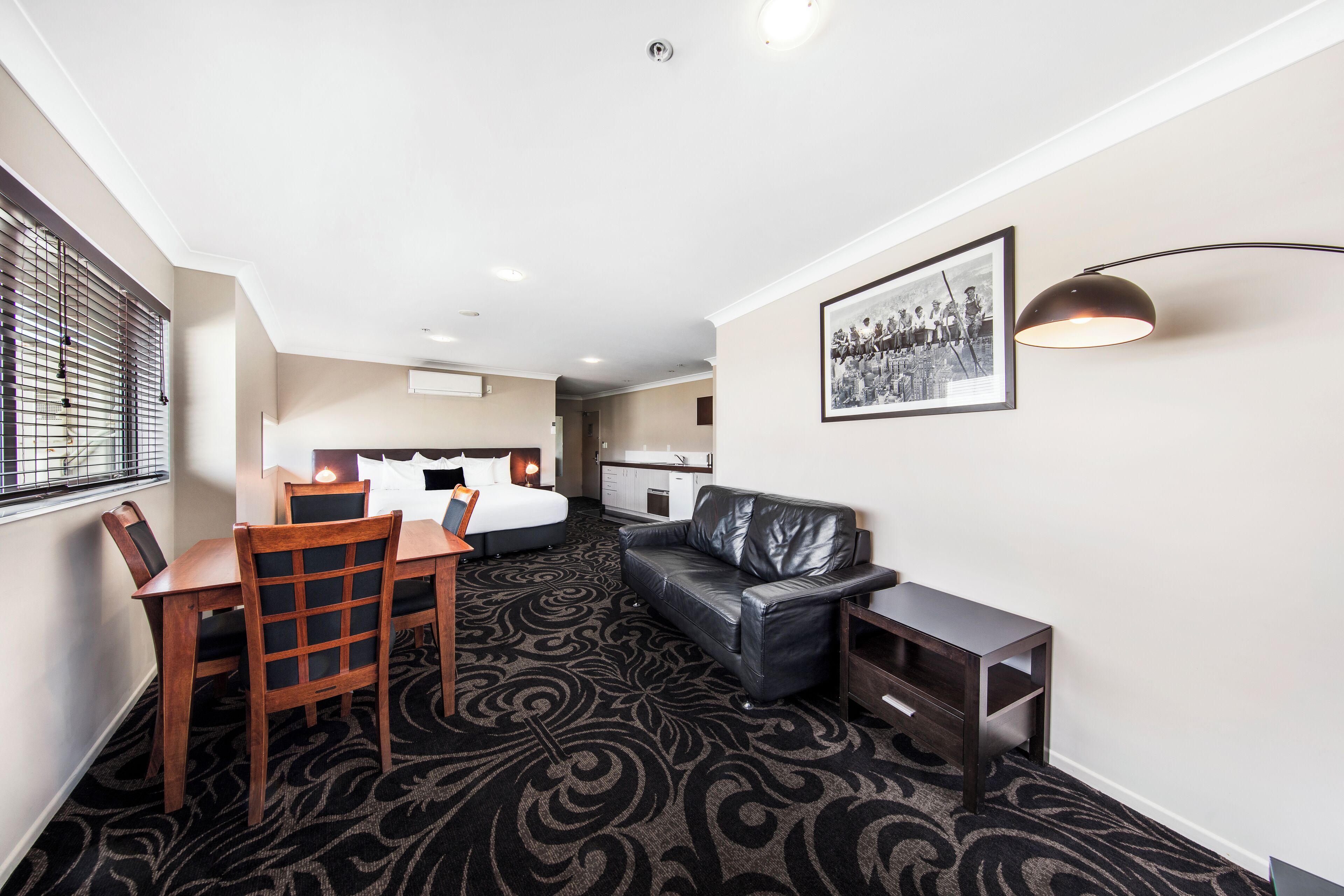 Une chambre d’hôtel comprenant un coin repas, un canapé, une petite table et un tableau encadré au mur.