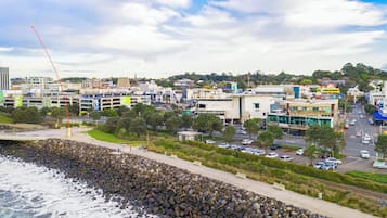 A coastal cityscape with a rocky shoreline, modern buildings, and a busy street.