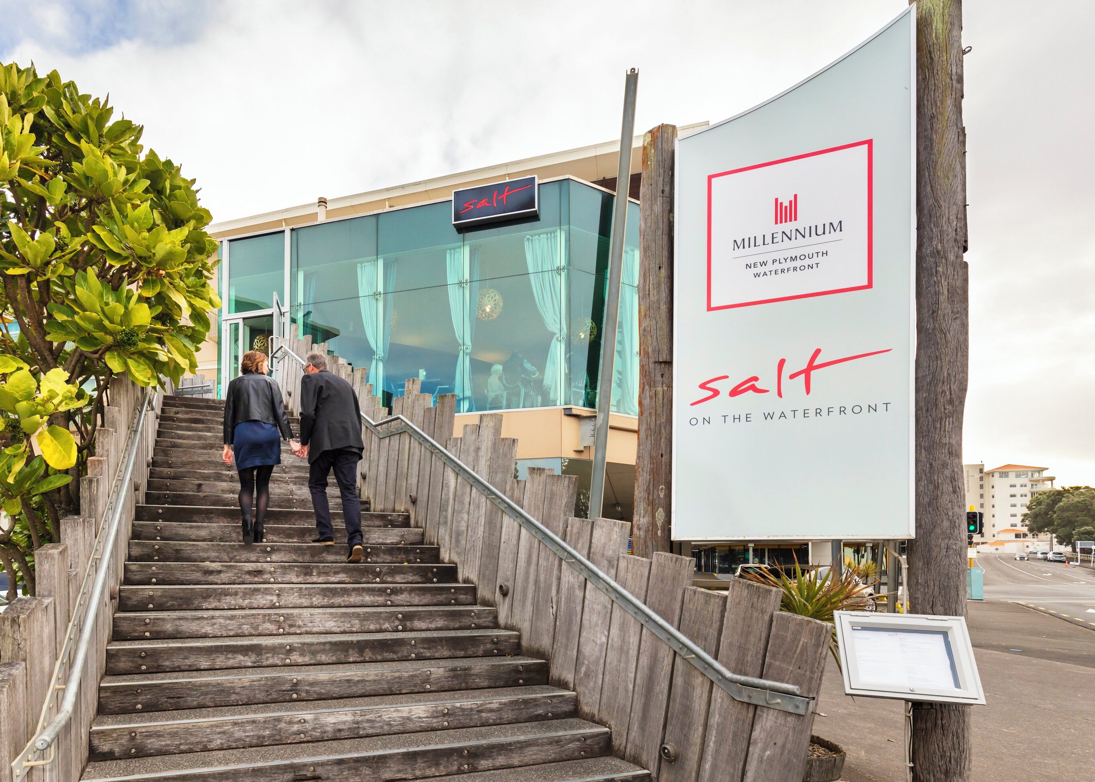 A staircase leading to a modern building with a sign reading "salt" and "Millennium New Plymouth Waterfront."