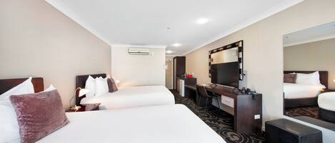 Une chambre d’hôtel avec deux lits, un bureau, un miroir et un sol recouvert de moquette.