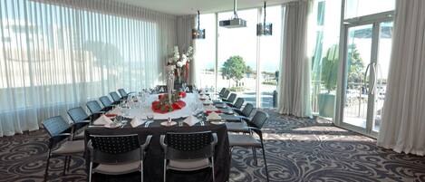 A conference room with a large table, chairs, and a view of the outdoors.