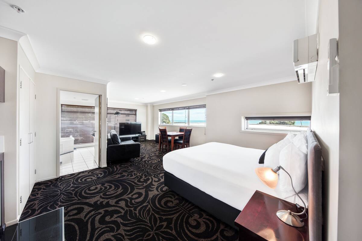 Habitación de hotel con una cama grande, un escritorio, una silla y vistas al exterior a través de la ventana.