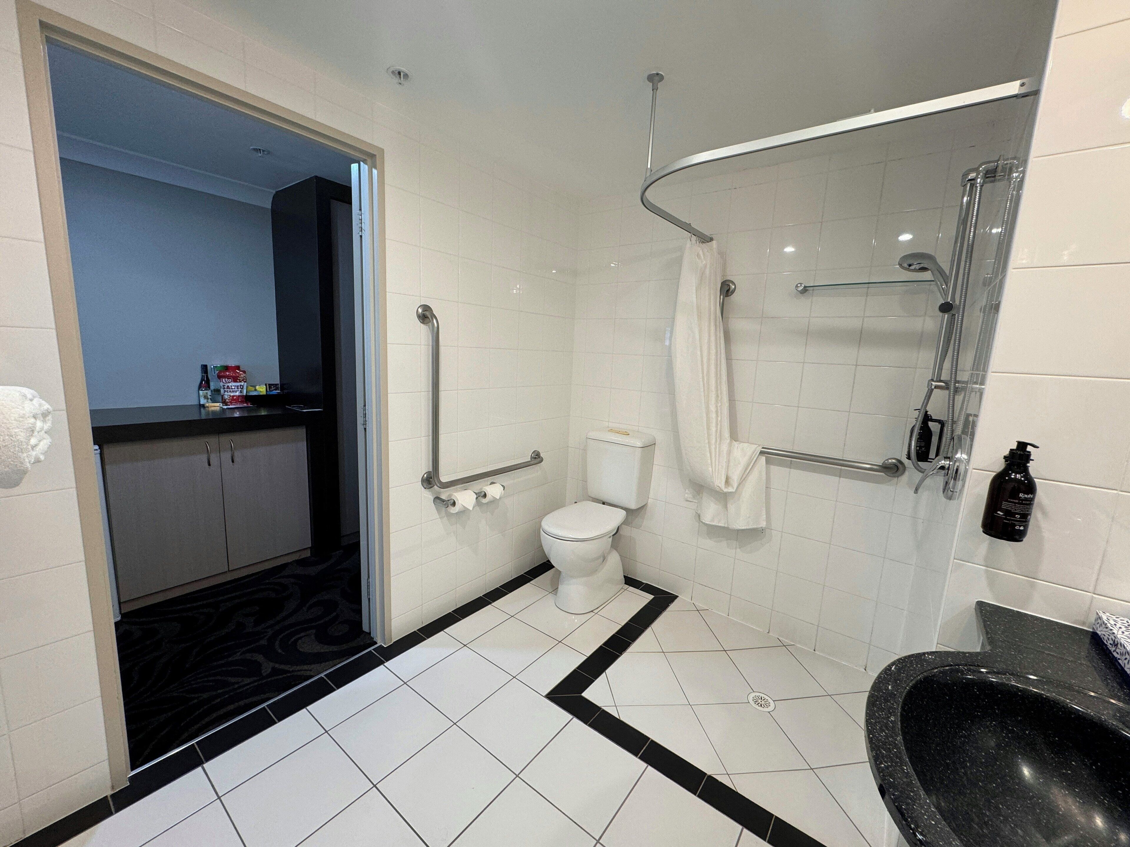 A modern bathroom with a white toilet, a black sink, and a shower area.