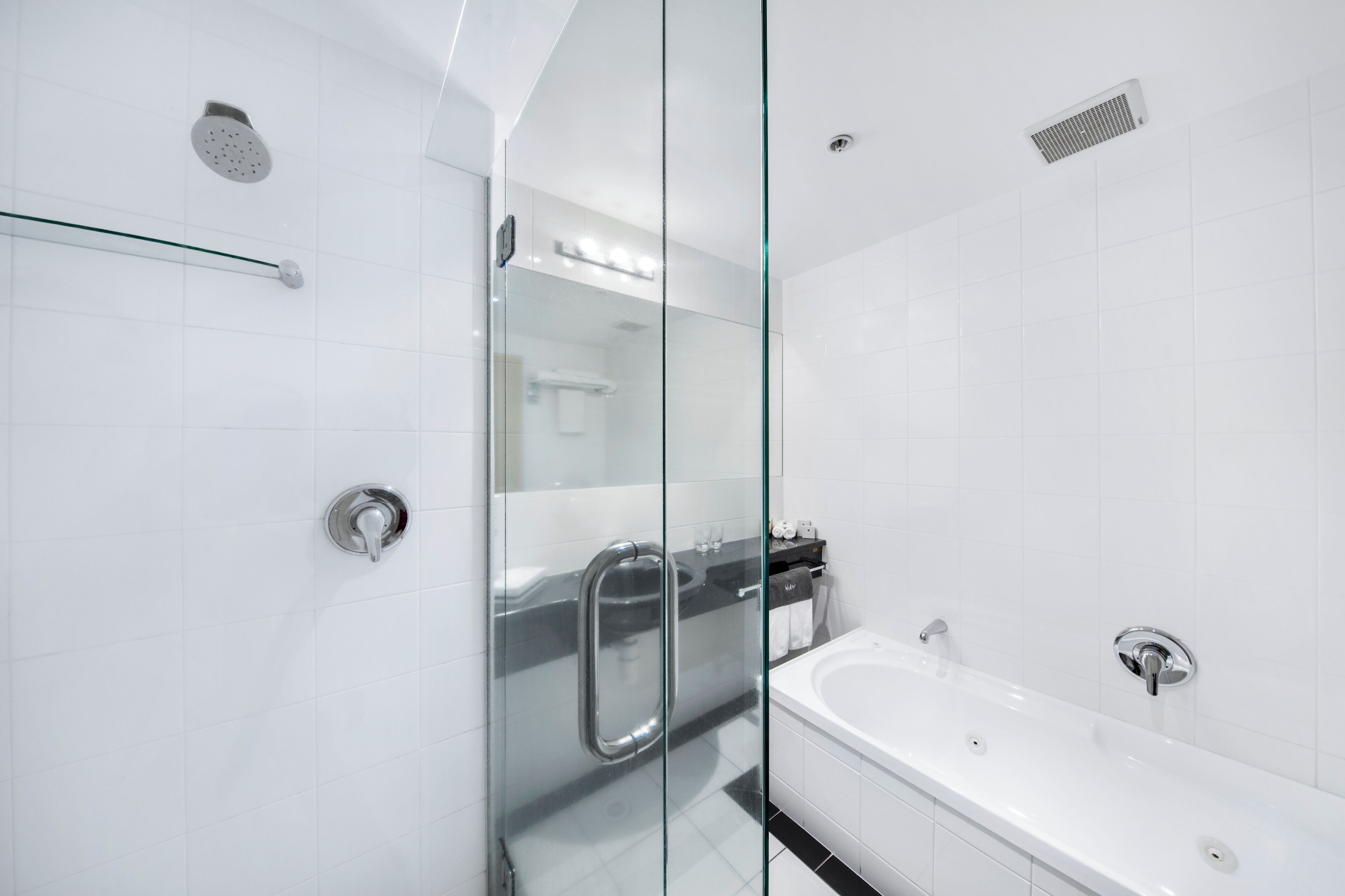 Un baño moderno con cabina de ducha de vidrio, una bañera y una puerta de cristal.