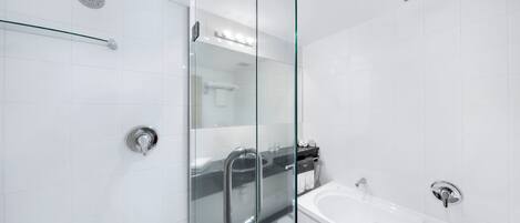 Un baño moderno con cabina de ducha de vidrio, una bañera y una puerta de cristal.