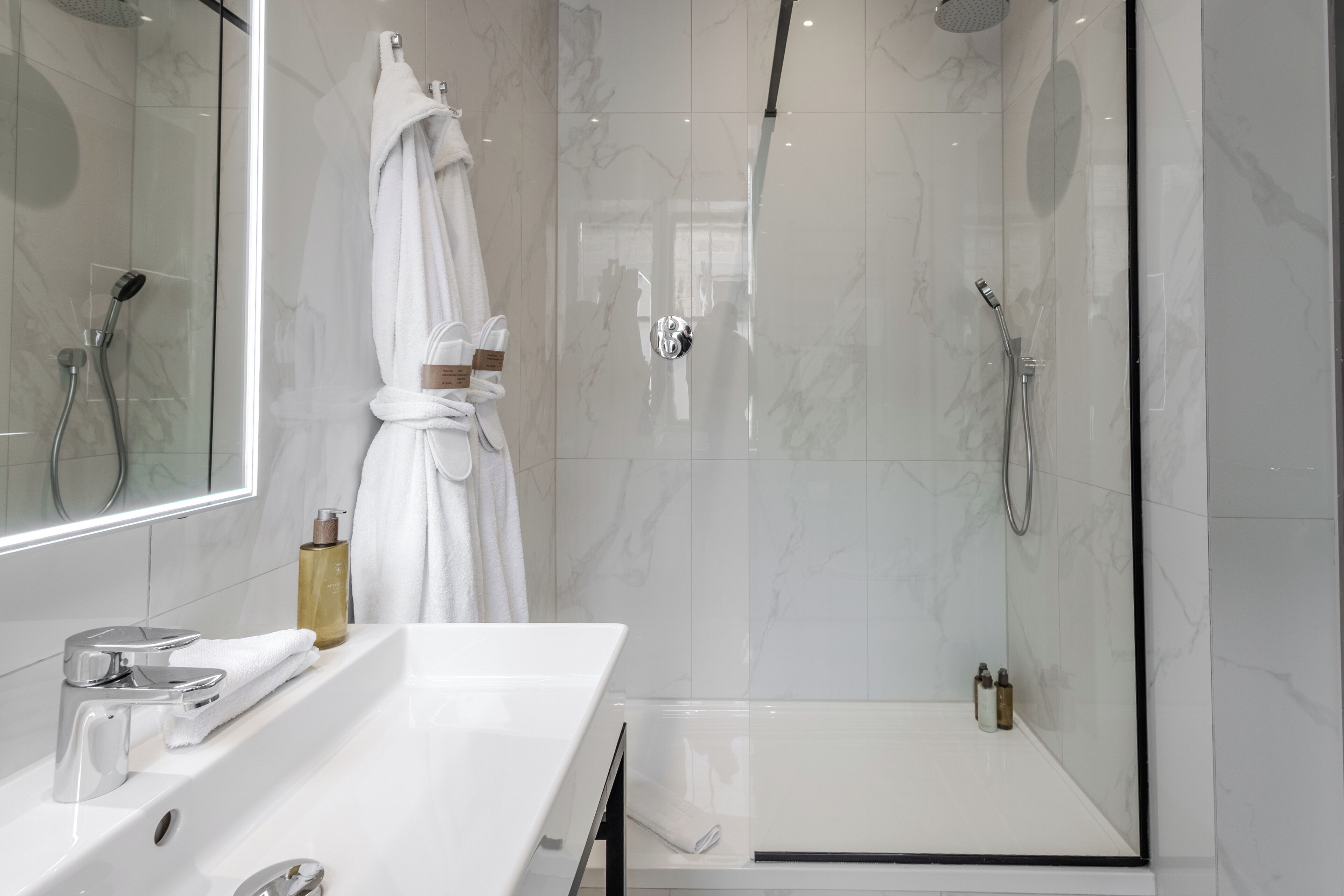 A modern bathroom with a glass-enclosed shower, a white sink with a mirror, and a towel rack.