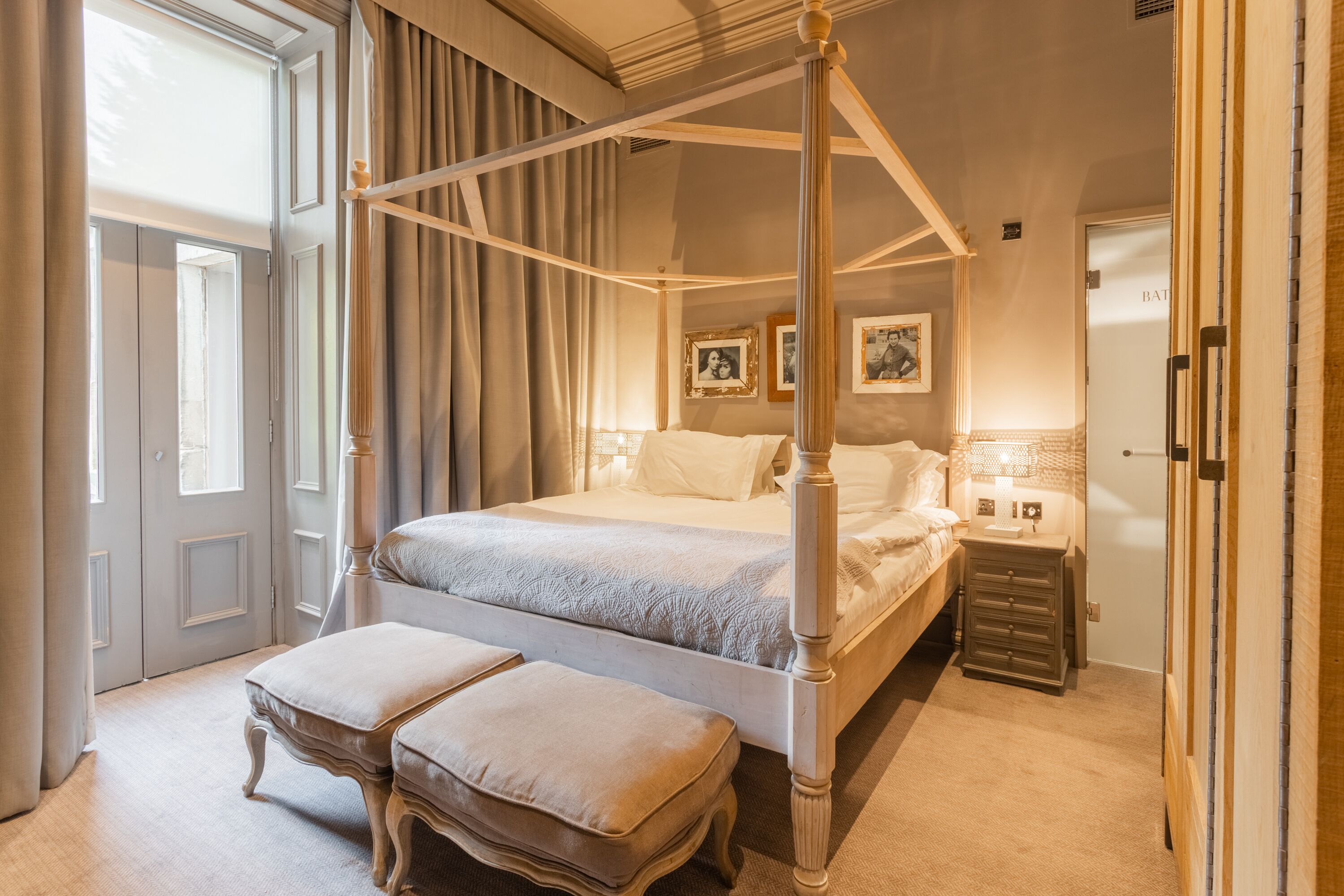 A four-poster bed with a nightstand and a small table beside it.