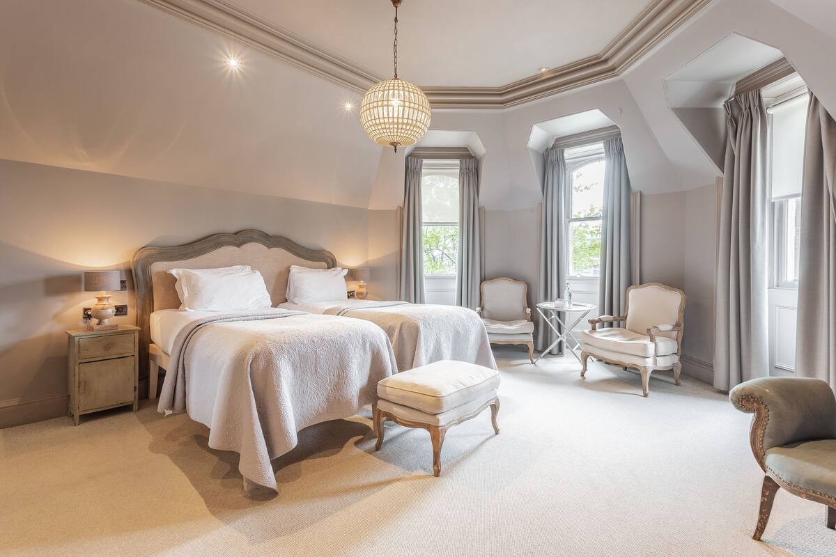 Ein geräumiges Schlafzimmer mit einem großen Bett, zwei Nachttischen, einem Sessel und einem kleinen Tisch.
