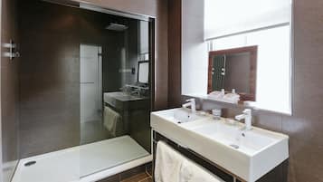 Une salle de bain moderne dotée d’une douche à parois de verre, de deux vasques et d’un grand miroir.