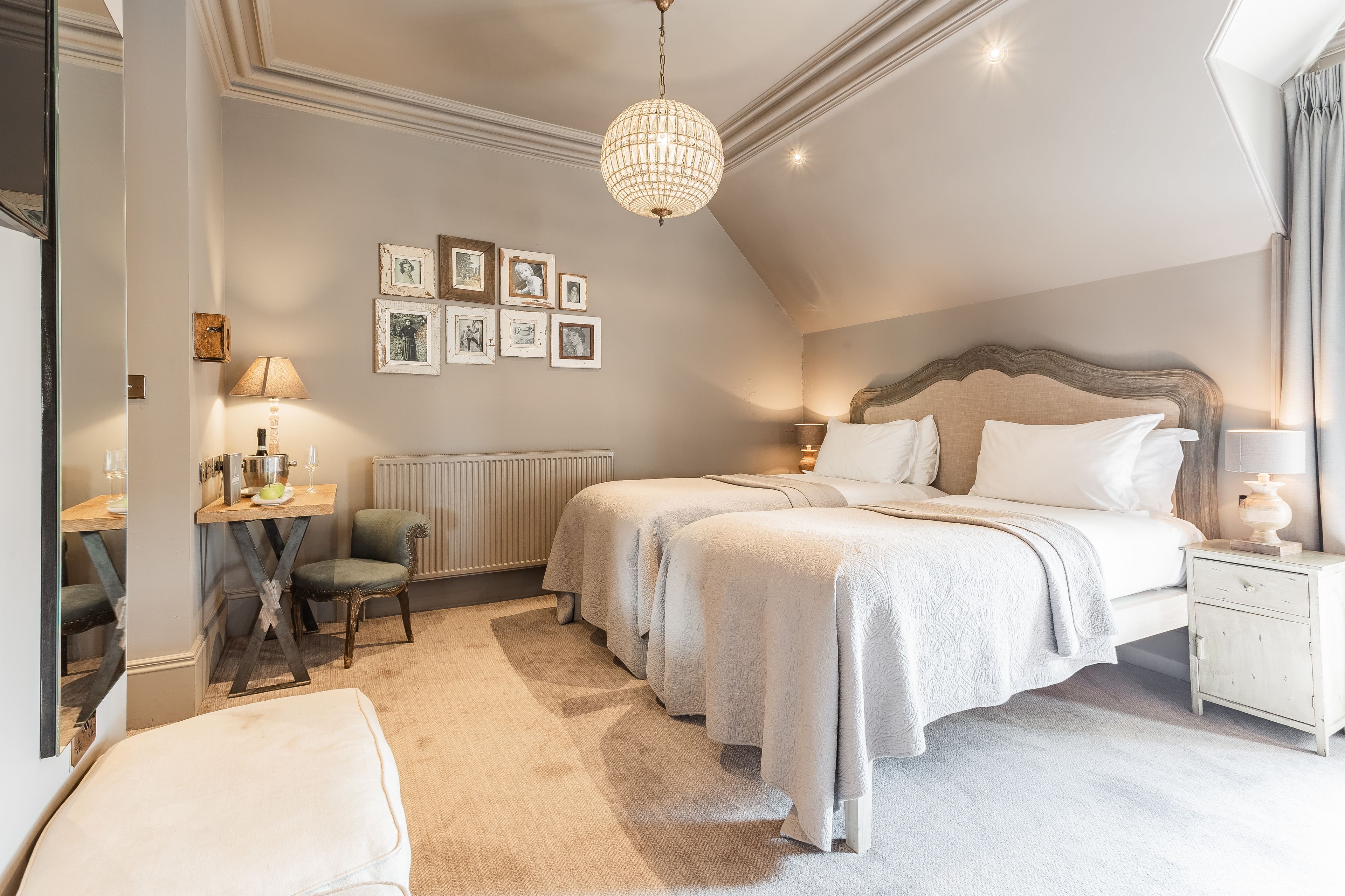 A bedroom with two beds, a desk, a chair, and a nightstand.