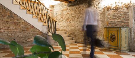 Una escalera con piso a cuadros que lleva a una habitación con pared de piedra y techo de madera.
