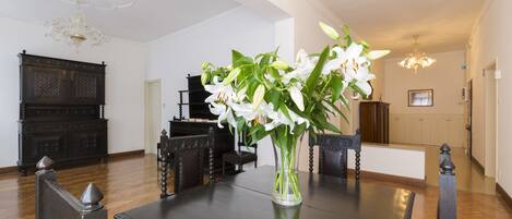 A dining area with a dark wooden table, chairs, and a vase of white flowers.