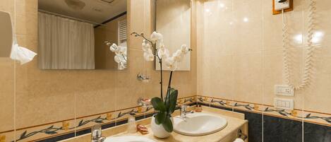 A bathroom with two sinks, a mirror, a shower, and a hairdryer mounted on the wall.