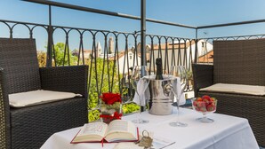 A table set for two with wicker chairs, a book, a bottle of champagne, and a bowl of strawberries. - Palazzo Guardi (Venice)