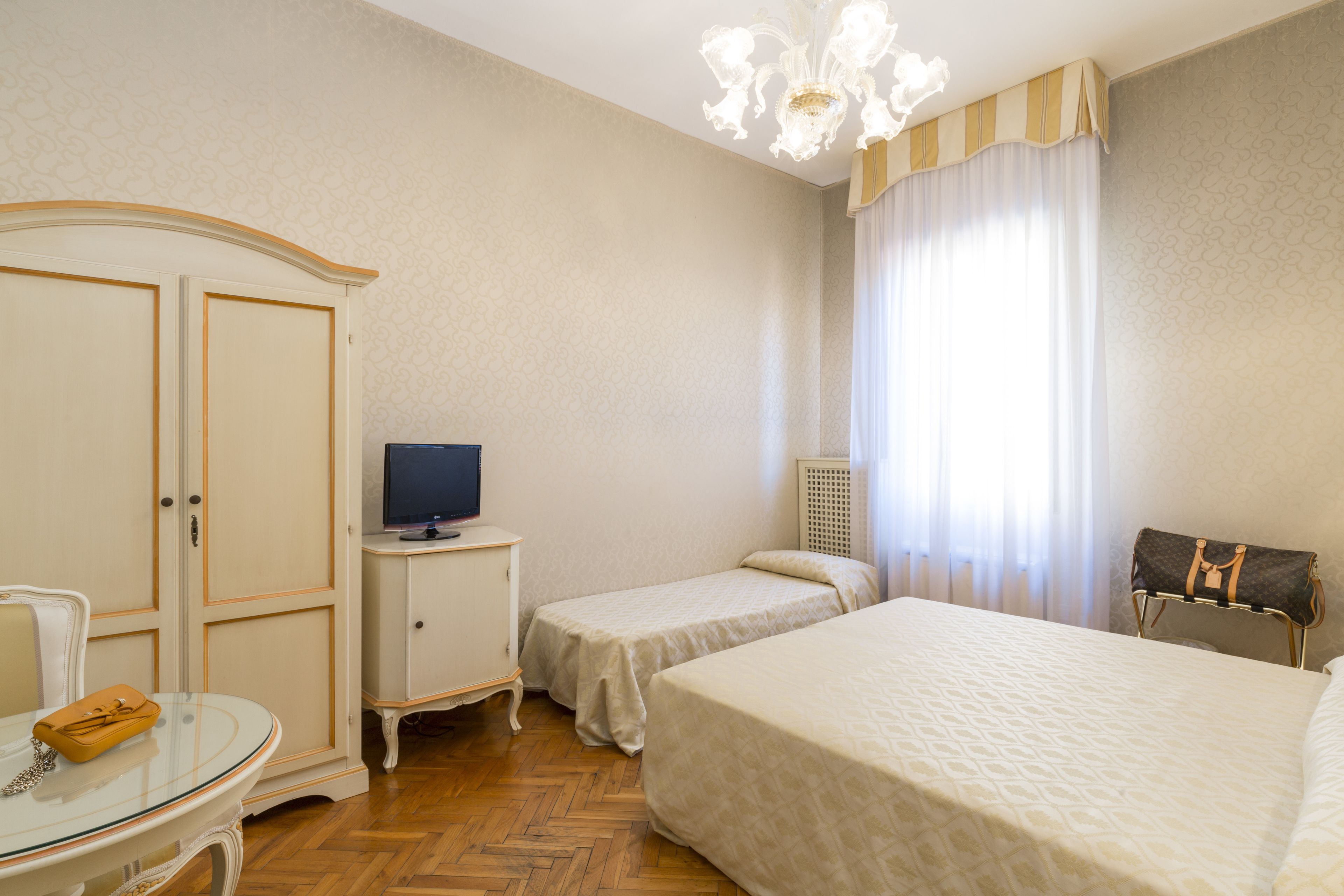 Ein Hotelzimmer mit einem Bett, einem Fernseher, einem Schrank und einem Tisch mit Stuhl.