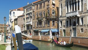 A canal with a gondola, buildings with balconies, and a bridge. - Palazzo Guardi (Venice)