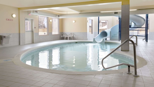 An indoor swimming pool with a slide, a no diving sign, and a view of the outside. - Days Inn by Wyndham Moose Jaw (Moose Jaw)