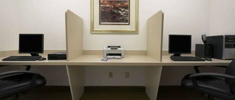 A workspace with two desks, each with a computer and keyboard, a printer, and a framed picture on the wall.