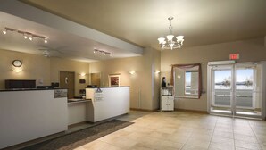 A reception area with a reception desk, a clock, a chandelier, and an exit sign. - Days Inn by Wyndham Moose Jaw (Moose Jaw)