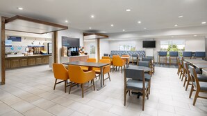 A modern cafe with a breakfast bar, seating area, and a TV screen. - Holiday Inn Express Las Vegas - Stadium Area by IHG (Las Vegas)