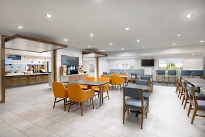 A modern cafe with a breakfast bar, seating area, and a TV screen. - Holiday Inn Express Las Vegas - Stadium Area by IHG (Las Vegas)