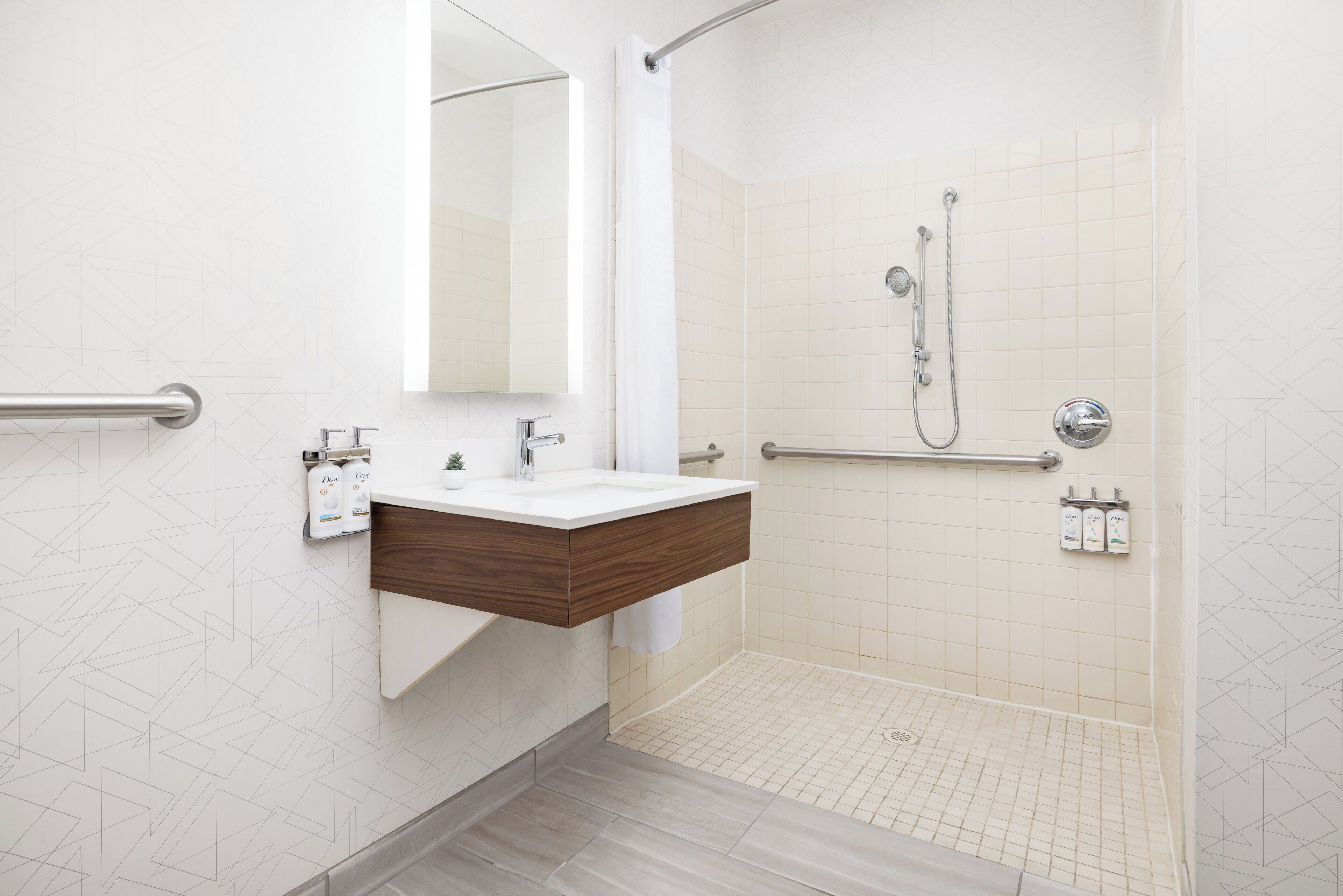 A modern bathroom with a shower, a sink with a wooden vanity, and handrails.