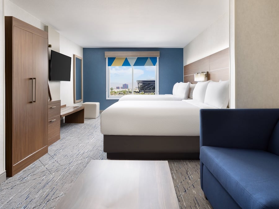 A hotel room with a bed, a blue sofa, a TV, and a wardrobe.