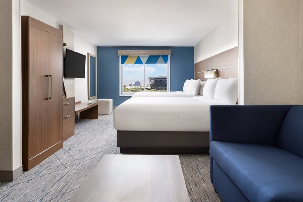 A hotel room with a bed, a blue sofa, a TV, and a wardrobe. - Holiday Inn Express Las Vegas - Stadium Area by IHG (Las Vegas)