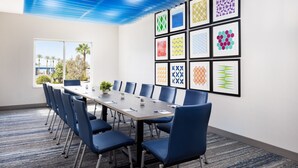 A conference room with a long table, blue chairs, and framed geometric patterns on the wall. - Holiday Inn Express Las Vegas - Stadium Area by IHG (Las Vegas)