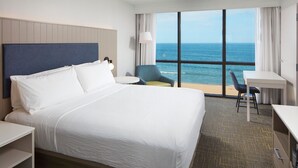 A hotel room with a large bed, a desk, a chair, and a view of the ocean. - Four Points By Sheraton Virginia Beach Oceanfront (Virginia Beach)