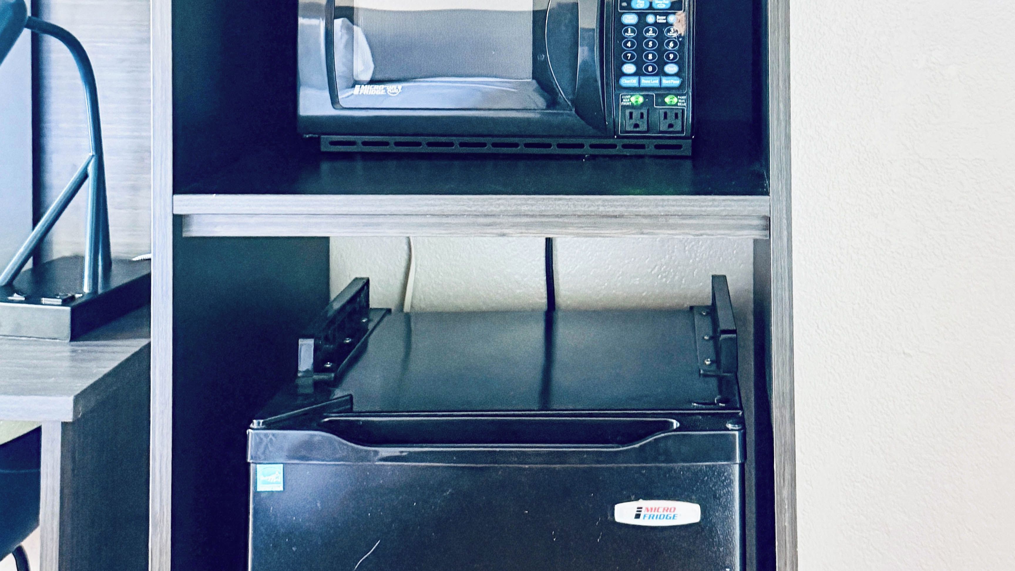 Cozinha com micro-ondas e geladeira preta com etiqueta.