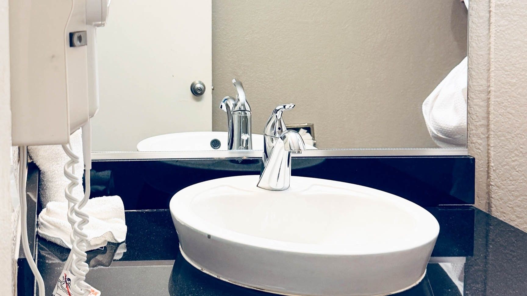 A bathroom with a white sink, a mirror, and a towel rack.