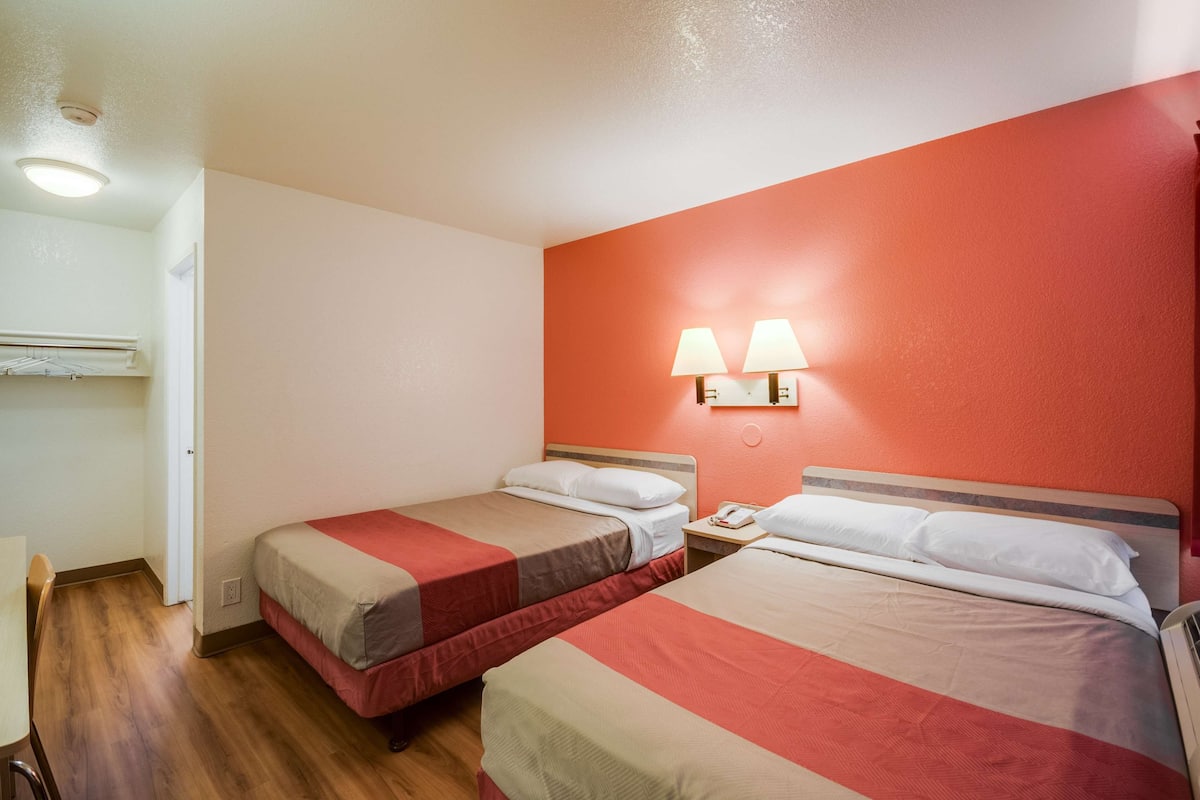 Una habitación de hotel con dos camas, un escritorio y una silla.