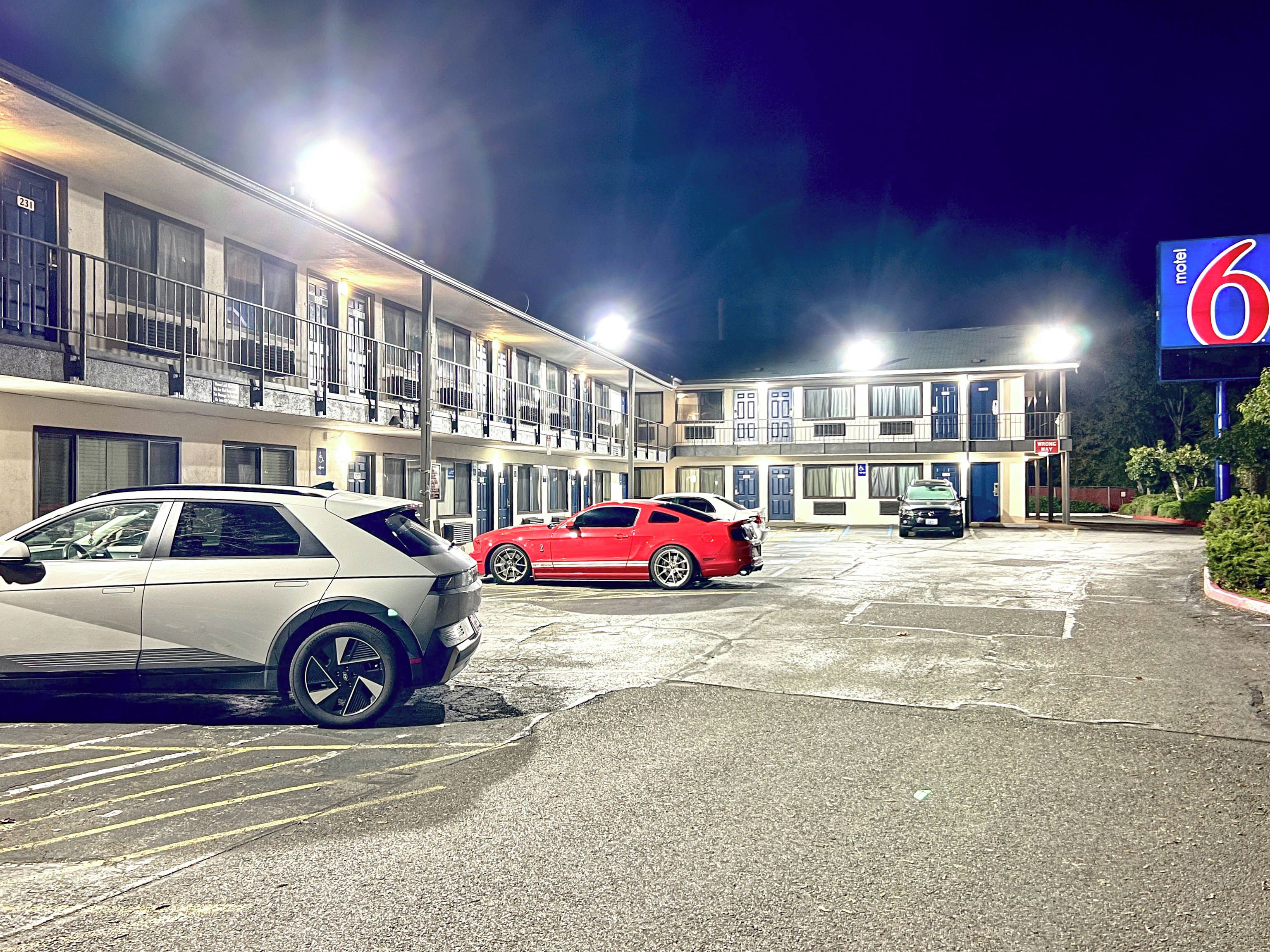A motel with a two-story building, a parking lot, and a sign indicating the motel number.