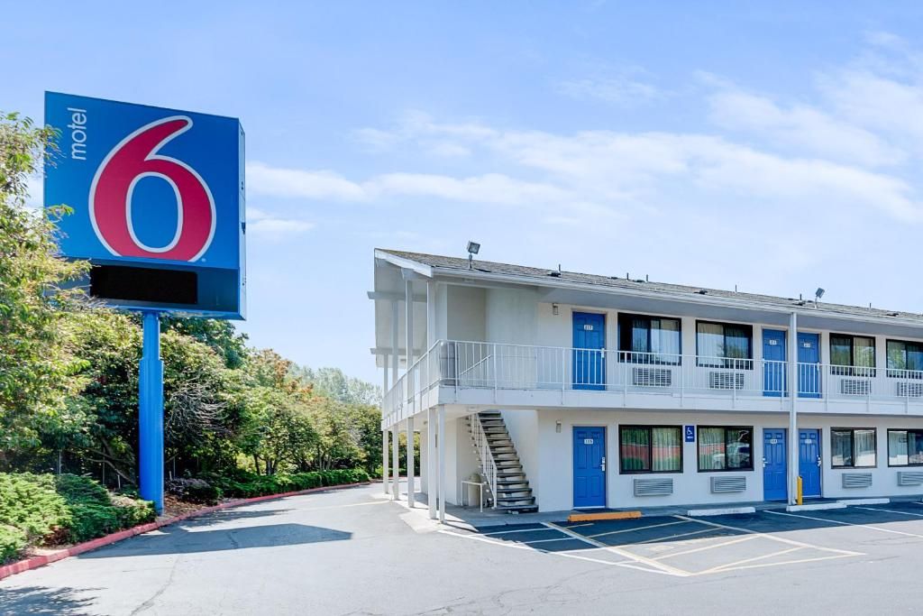 A motel with a prominent sign, a two-story building, a parking lot, and a staircase leading to the entrance.
