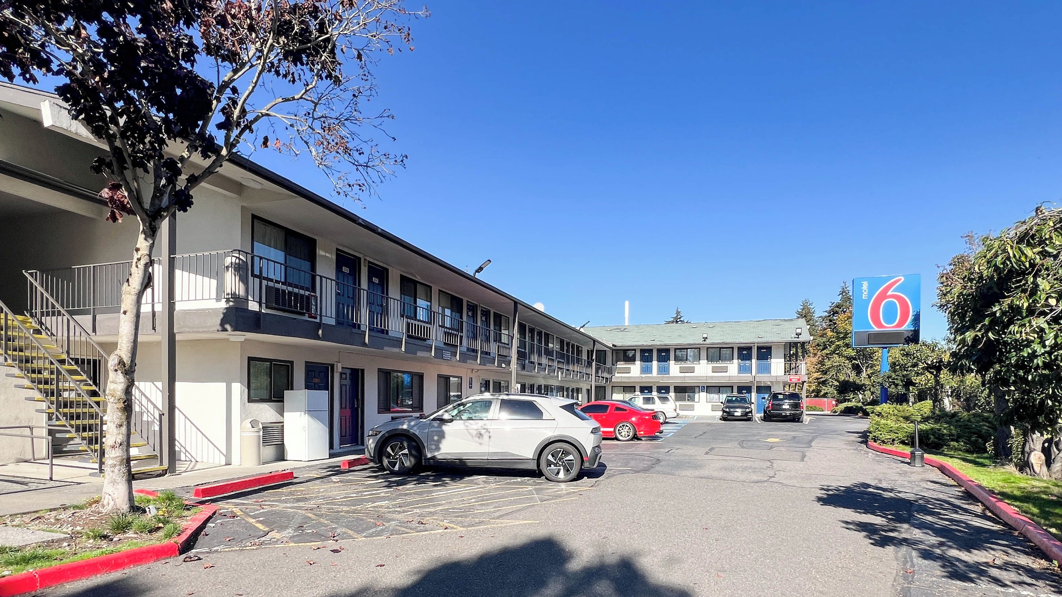 Ein Motel mit Parkplatz, mehrstöckigen Gebäuden und blauem Himmel.