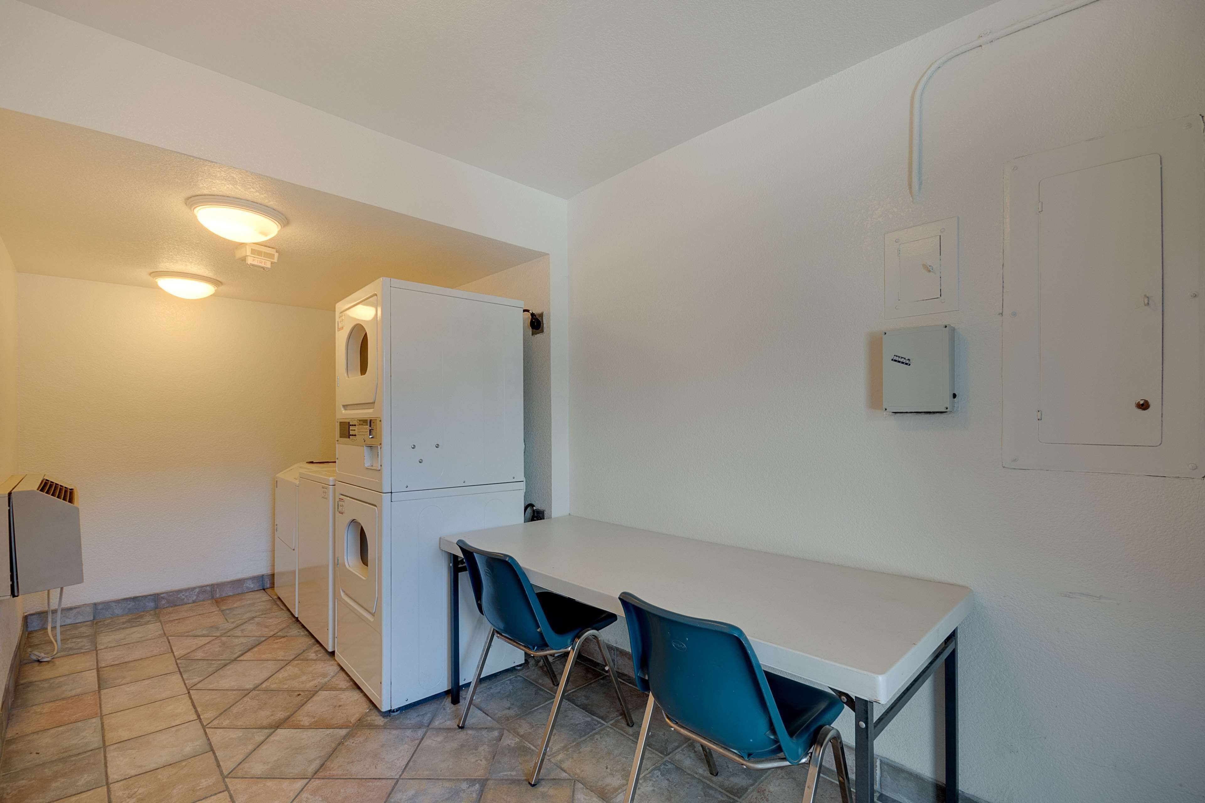 A compact kitchen with a washing machine, a small table, and two chairs.