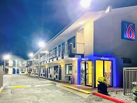 A motel with a '6' sign, multiple rooms, and a welcoming entrance.