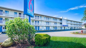 A motel with a prominent '6 ENTER' sign, multiple balconies, and a well-maintained lawn. - Motel 6 Warren, MI - Detroit East (Warren)