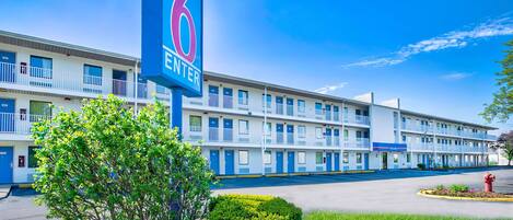 Un motel con un llamativo letrero que dice '6 ENTER', varios balcones y un césped bien cuidado.