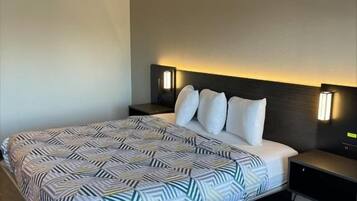 A modern hotel room with a large bed, bedside lamps, and a dark headboard.