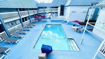 Ein Poolbereich mit Liegestühlen, Sonnenschirmen und einer überdachten Sitzgelegenheit.