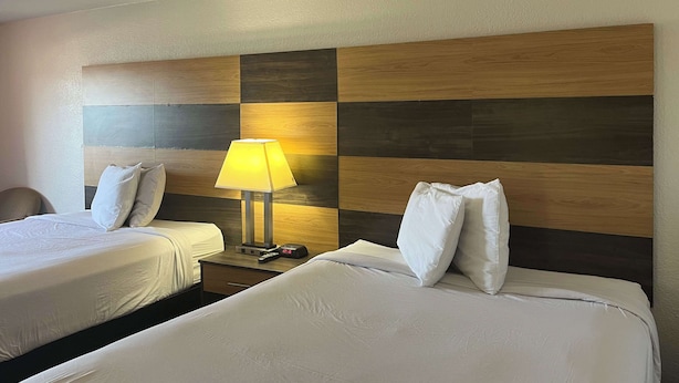 A hotel room with two beds, a nightstand with a lamp, and a clock. - Motel 6 Cross Lanes, WV - Goff Mountain Rd (Cross Lanes)